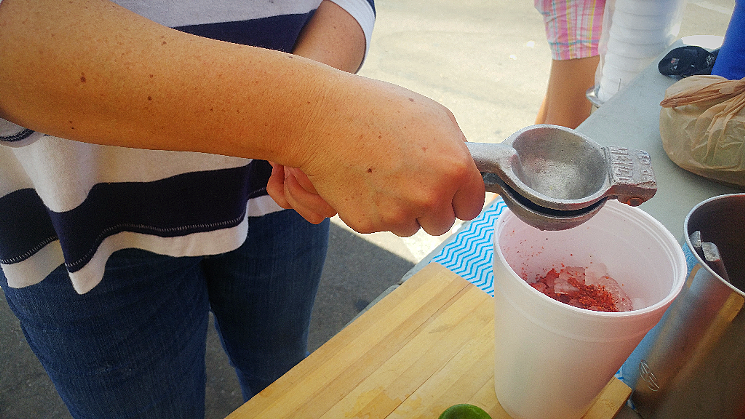 A street vendor squeezes some lime into a cup of tepache in west Phoenix. - PATRICIA ESCARCEGA