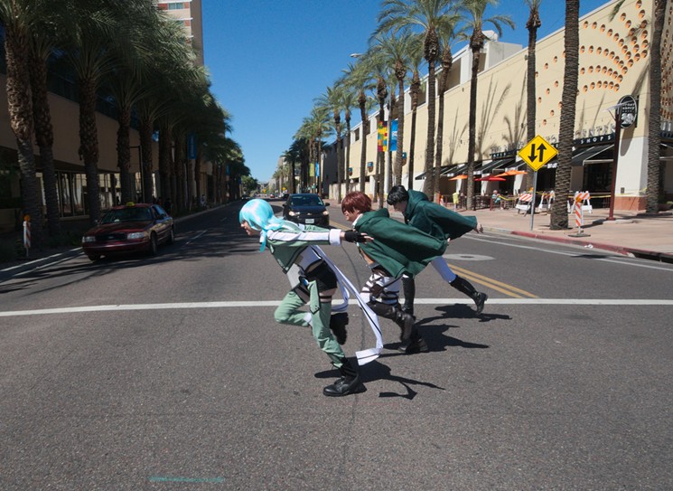 A trio of Attack on Titan cosplayers zoom through the crosswalk at Third and Van Buren streets outside of the Sheraton Grand Phoenix Hotel. - BENJAMIN LEATHERMAN