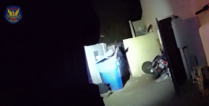 Image: body-cam footage at night of a hand holding something popping out of a blue recycling bin