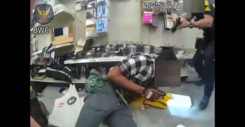 Image: body cam footage showing a police officer pointing a gun at a man on the ground
