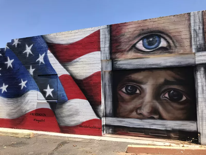 Image: a mural with an american flag and faces looking out from behind bars