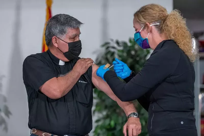 Image: DHS Director Dr. Cara Christ gives a religious leader his second dose of the COVID-19 vaccine at an event last month.