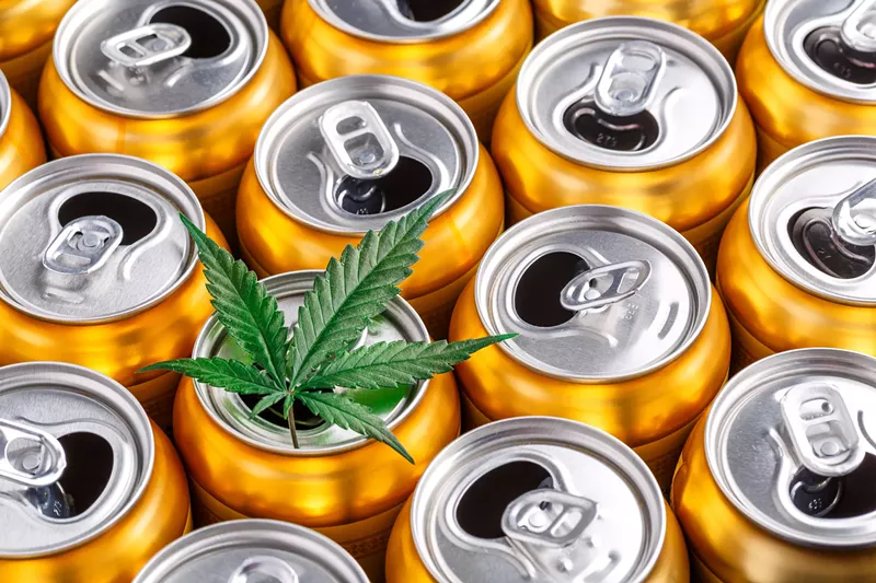 Image: open soda cans with a marijuana leaf on top
