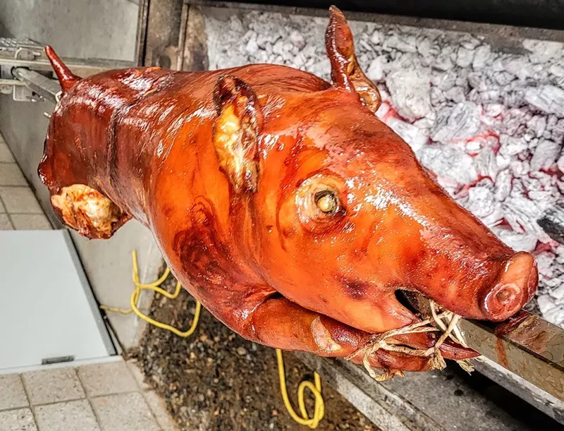 Image: Phx Lechon Roasters serving up a whole pig, roasting over charcoal.