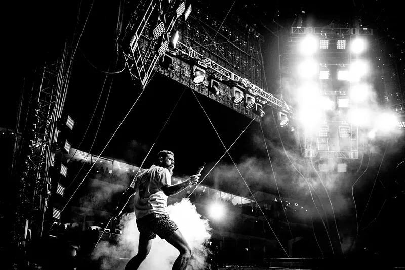 Image: A black and white photo of a man singing at concert.