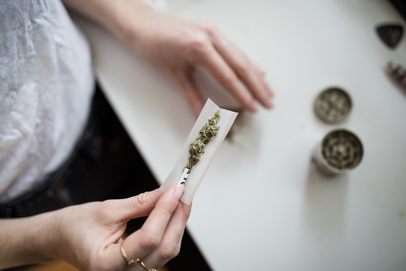 A woman rolls a marijuana joint.