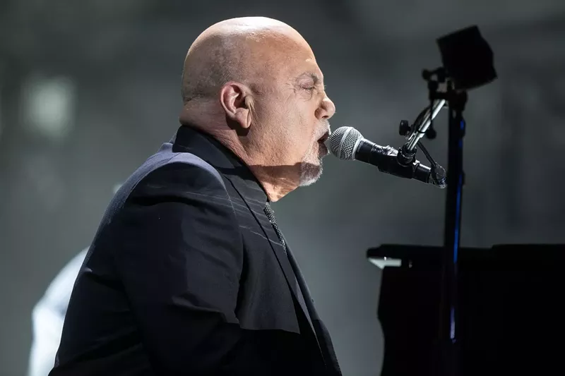 Image: Rock 'n' roll legend Billy Joel singing into a microphone.