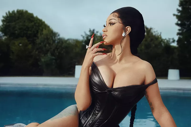 Image: Cardi B in a black dress next to a swimming pool